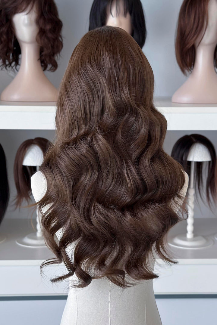 Brown wig on a mannequin head with blurred wigs in the background