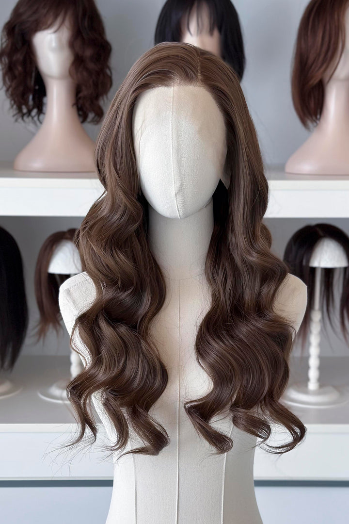 Brown wig on a mannequin head with blurred wigs in the background