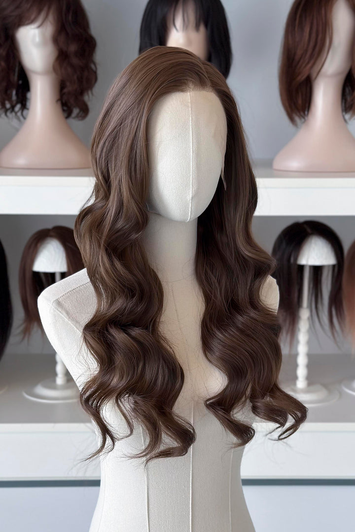 Brown wig on a mannequin head with blurred wigs in the background