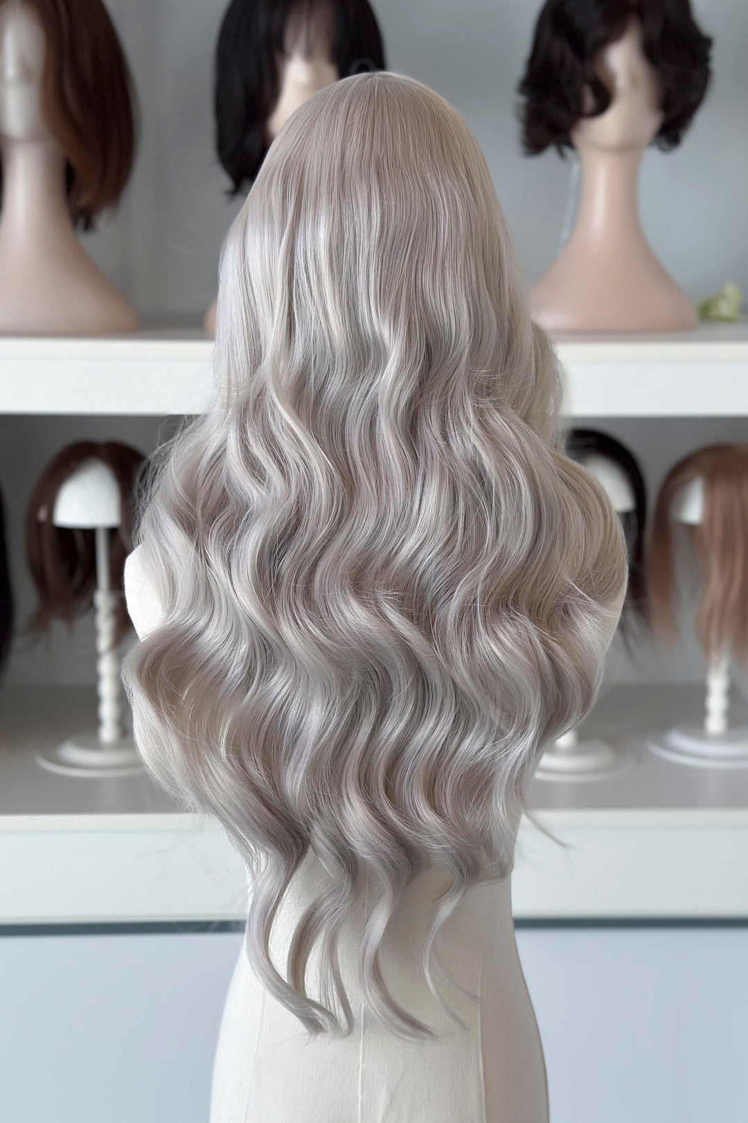 Silver lace front wig on a mannequin head with blurred wig display in the background