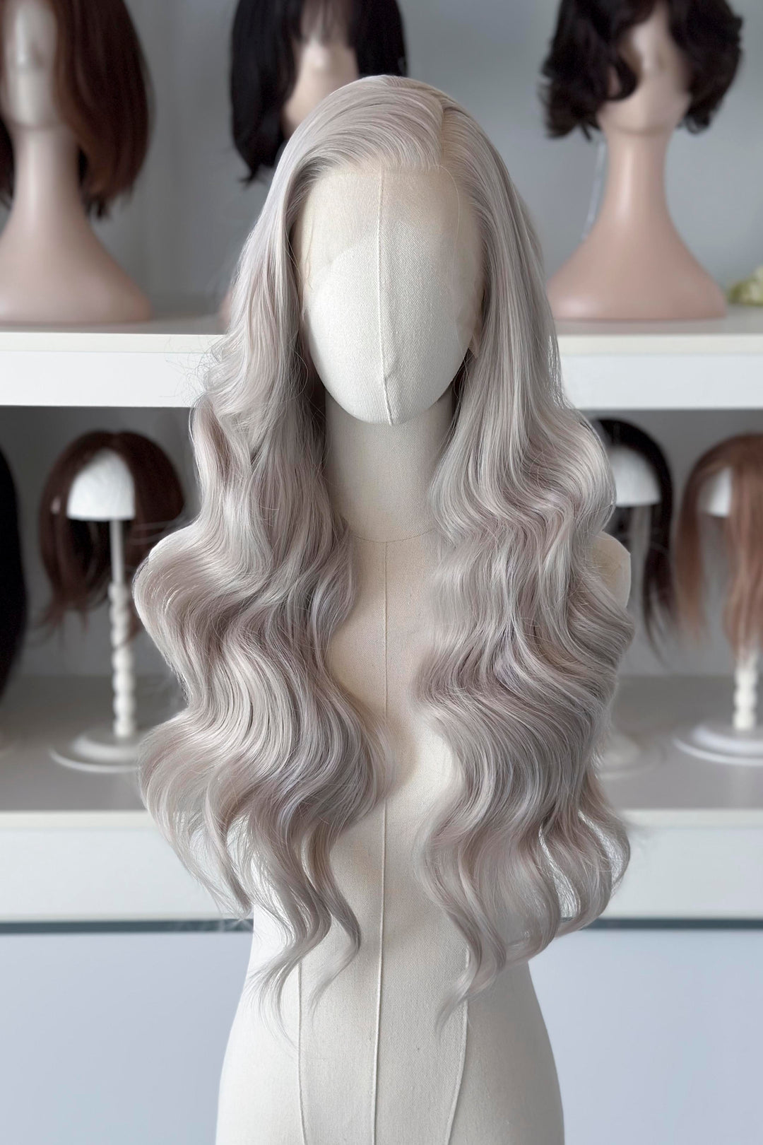 Silver lace front wig on a mannequin head with blurred wig display in the background
