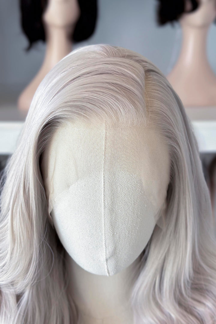 Silver lace front wig on a mannequin head with blurred wig display in the background