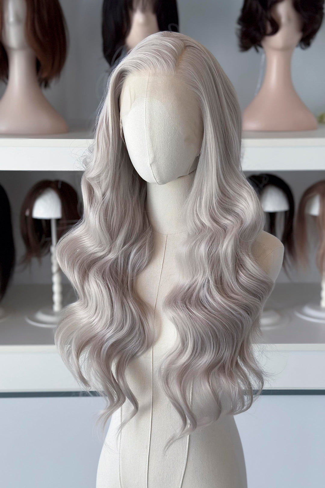 Silver lace front wig on a mannequin head with blurred wig display in the background