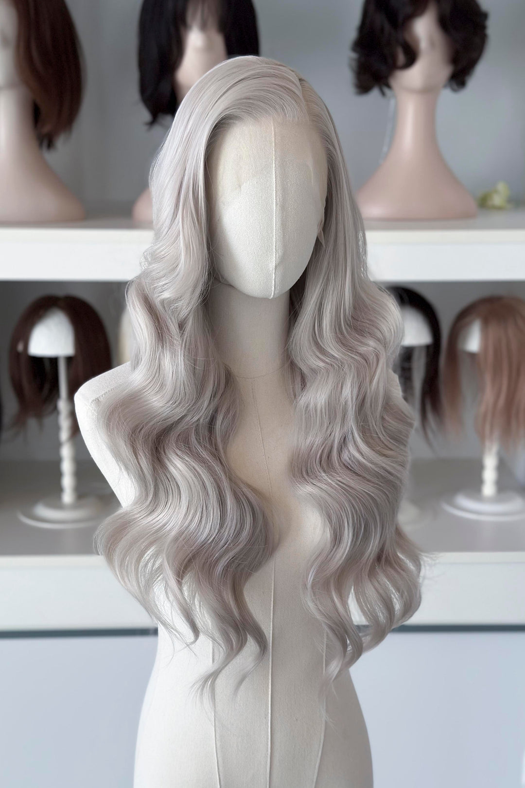Silver lace front wig on a mannequin head with blurred wig display in the background