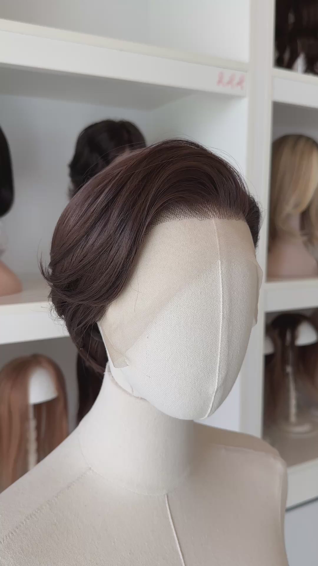 Brown short wig on a mannequin head with blurred wigs in the background