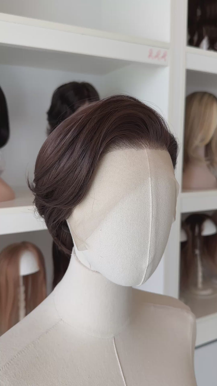 Brown short wig on a mannequin head with blurred wigs in the background