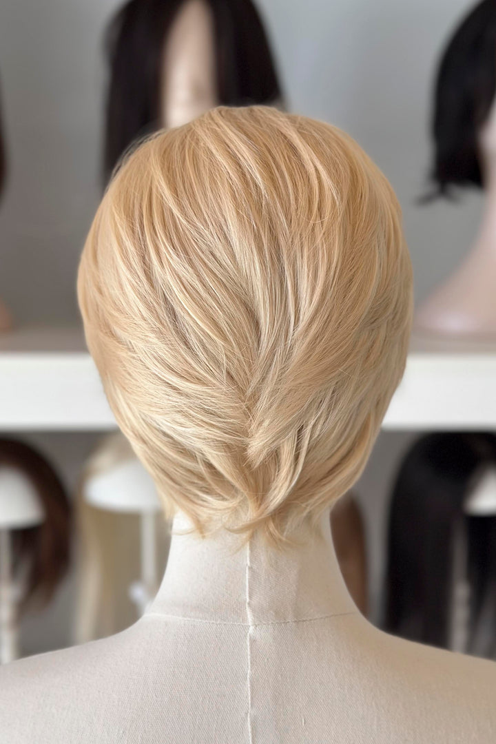 Blonde Short Lace wig on a mannequin head with blurred wig display in the background