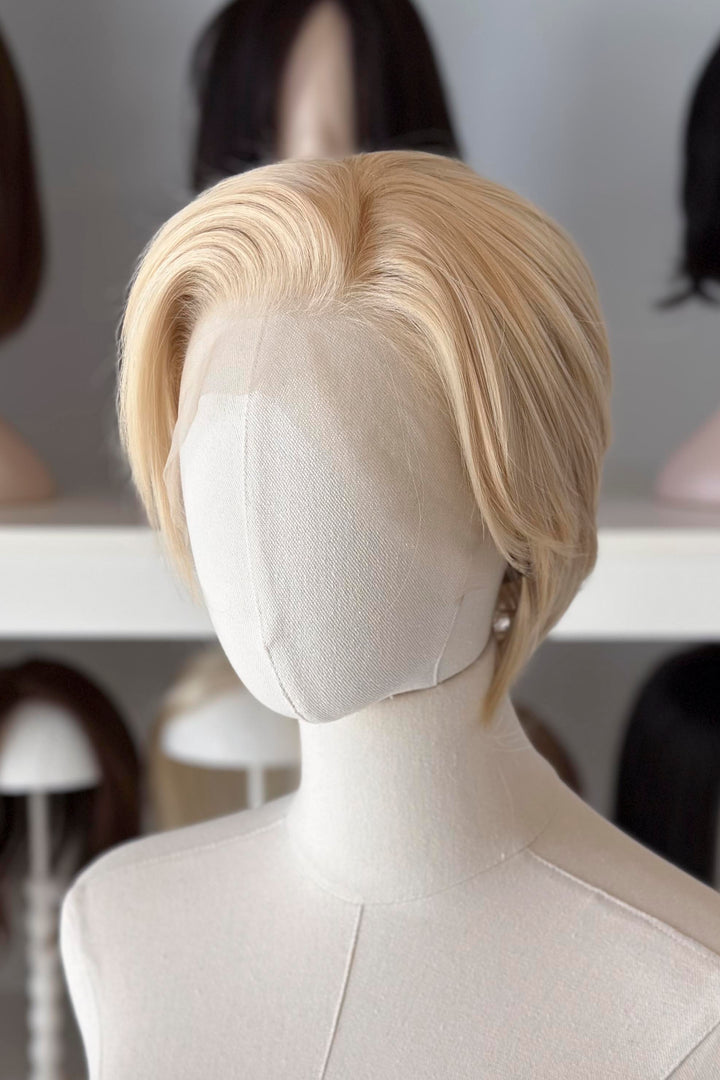 Blonde Short Lace wig on a mannequin head with blurred wig display in the background
