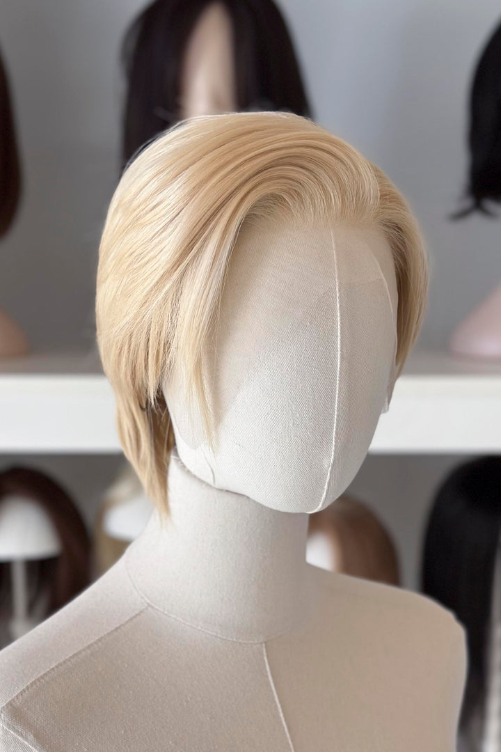 Blonde Short Lace wig on a mannequin head with blurred wig display in the background