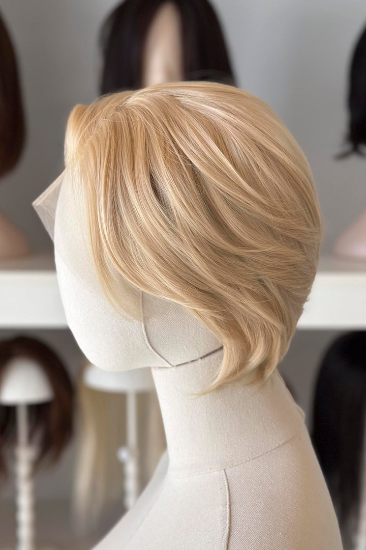 Blonde Short Lace wig on a mannequin head with blurred wig display in the background