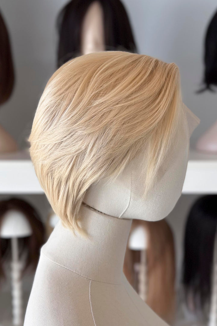 Blonde Short Lace wig on a mannequin head with blurred wig display in the background