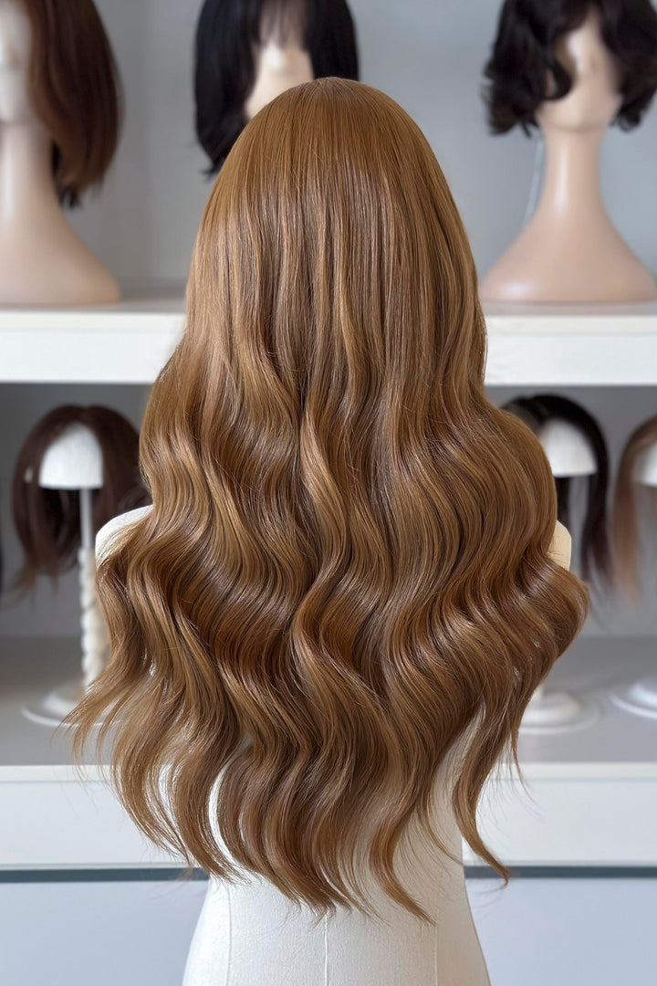  a long, wavy copper brown blonde wig in a wig store setting.
