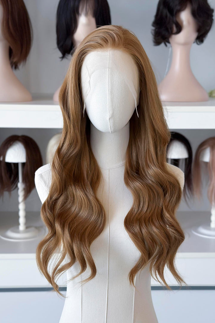  a long, wavy copper brown blonde wig in a wig store setting.