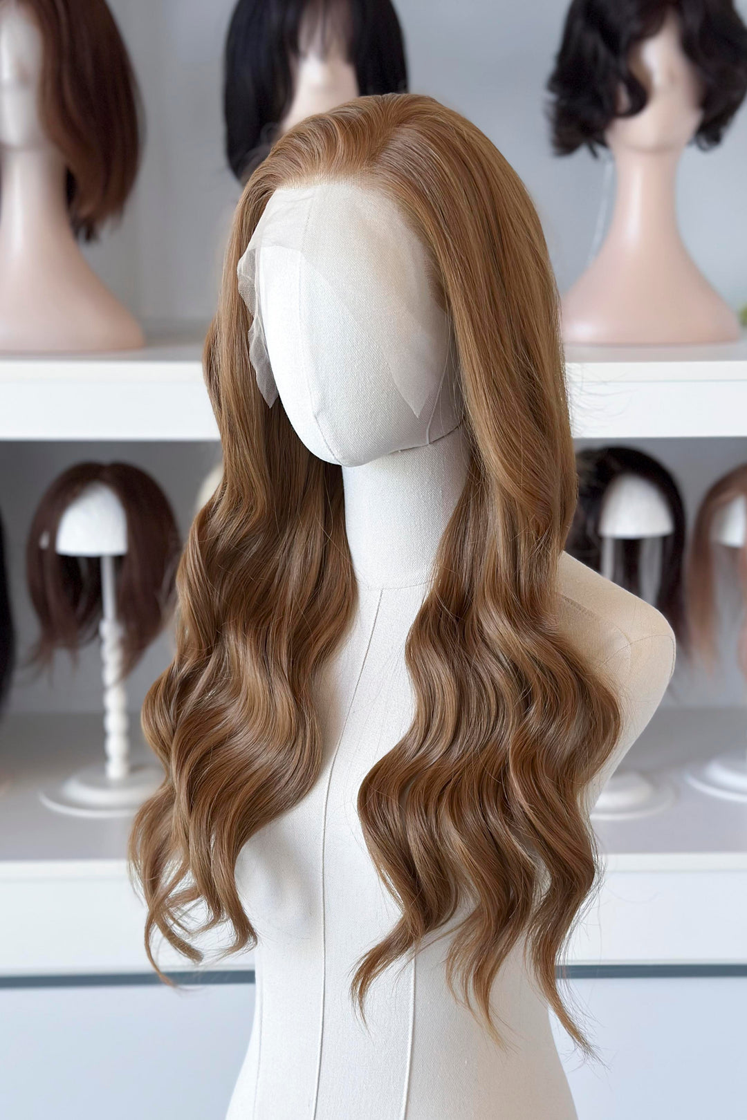  a long, wavy copper brown blonde wig in a wig store setting.