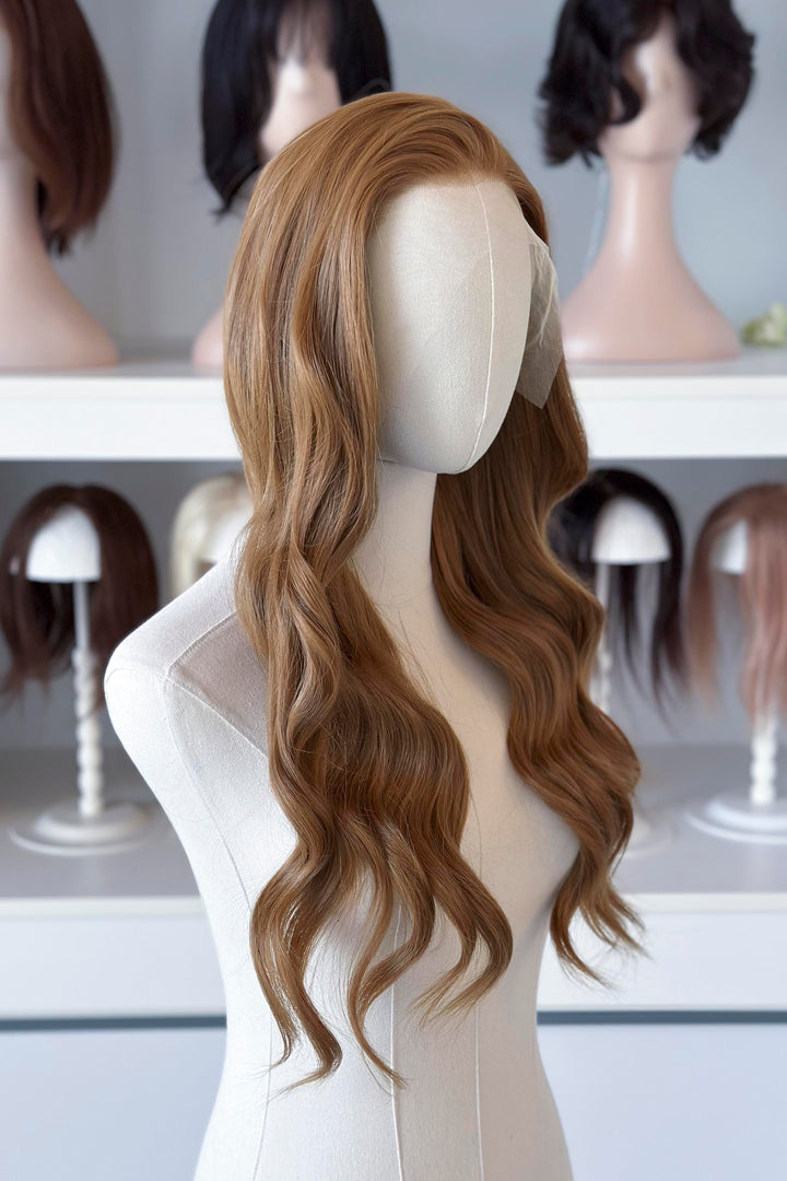  a long, wavy copper brown blonde wig in a wig store setting.
