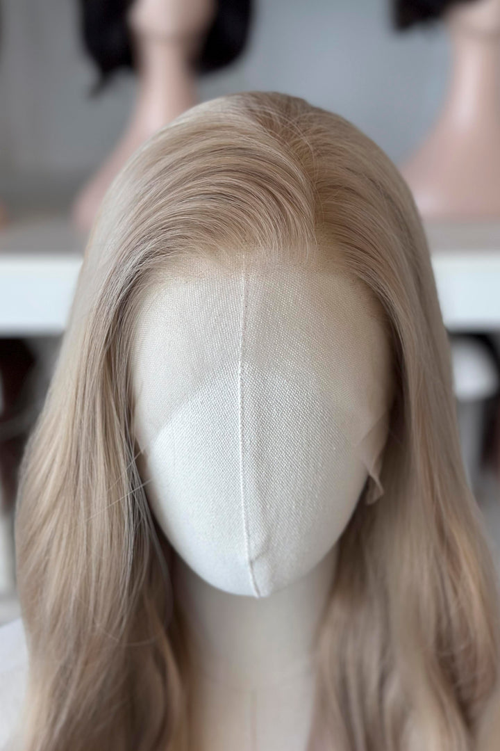 Light Golden Blonde wig on a mannequin head with blurred wig mannequins in the background, good for Aelin Galathynius cosplay