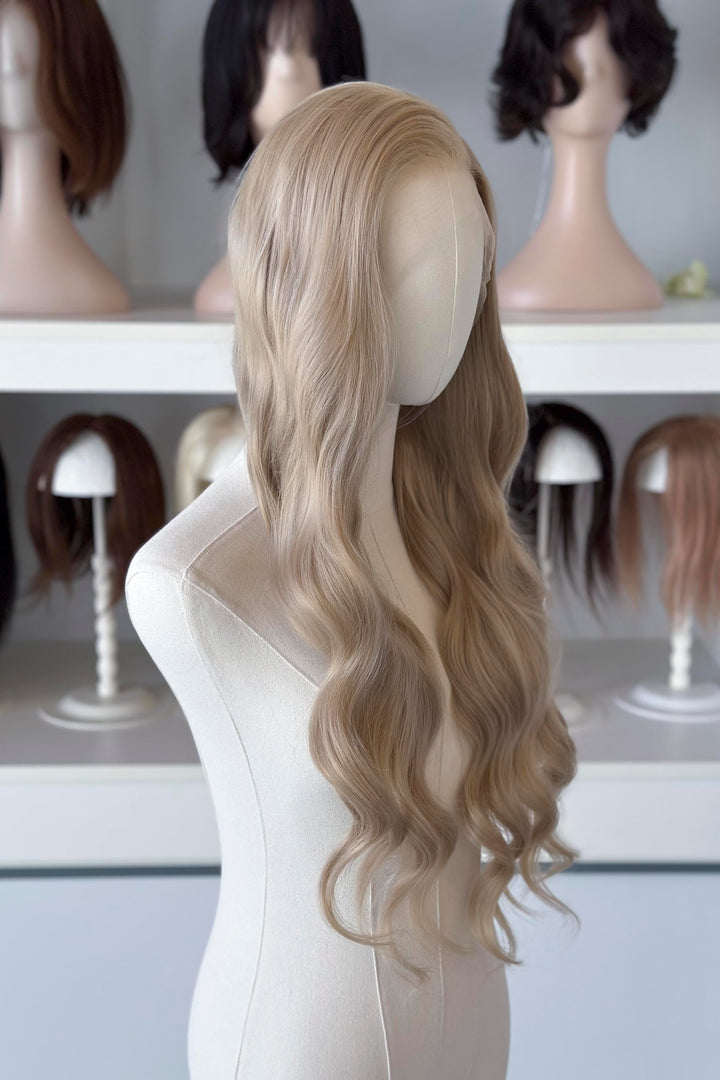 Light Golden Blonde wig on a mannequin head with blurred wig mannequins in the background, good for Aelin Galathynius cosplay